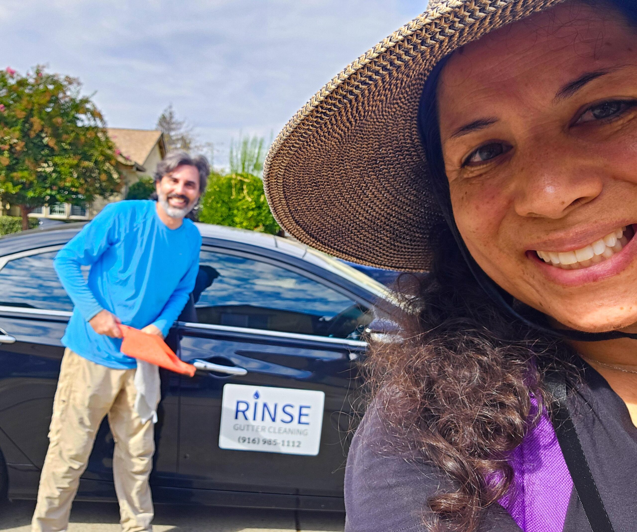 Darius and Shana the owners of Rinse Exterior cleaning by their sign.