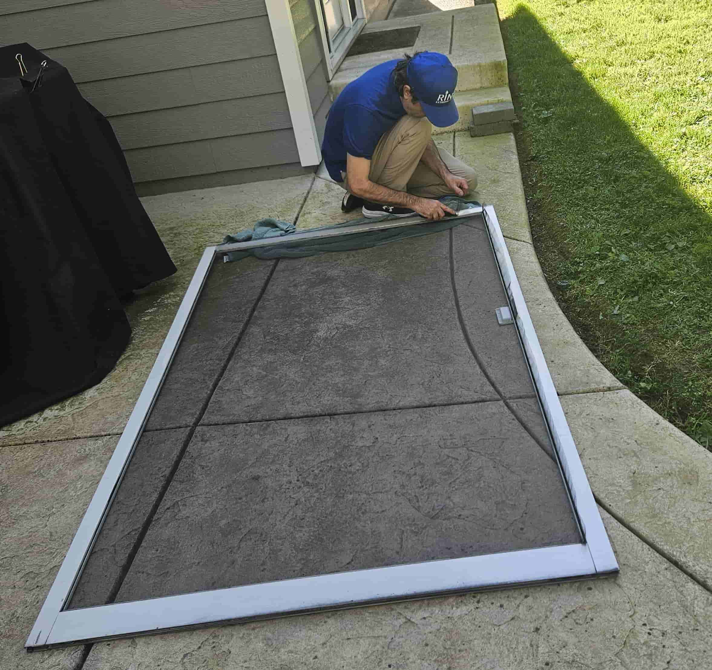 Man re-screening sliding patio door.