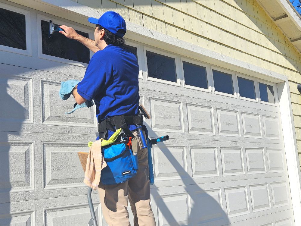 Man window cleaning a small window in a garage door.