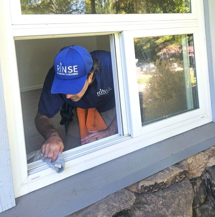 Man cleaning a window track with a towel.